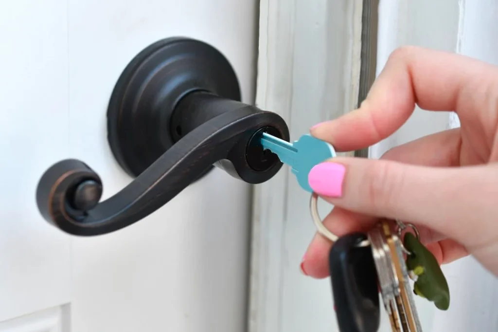 A female uses a key to unlock the door. Prevent house lockout.