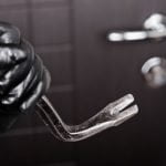 Burglar hand in gloves holding metal crowbar