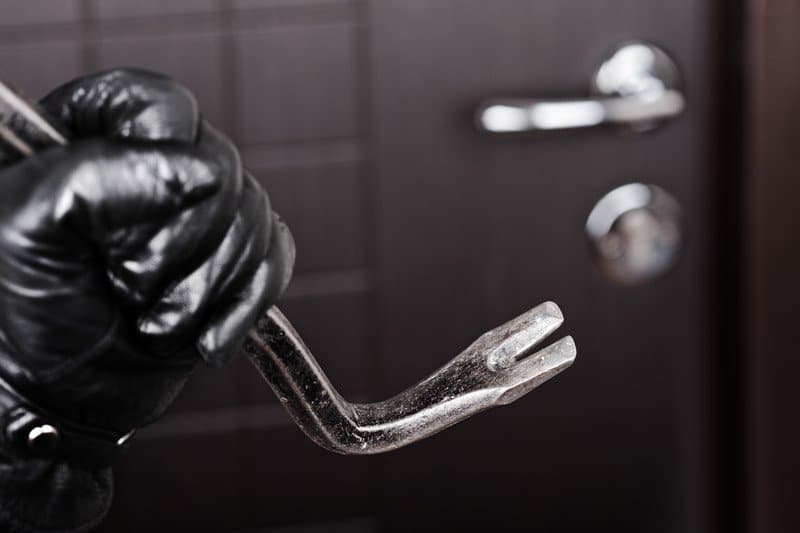 Burglar hand in gloves holding metal crowbar