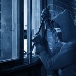 Burglar using crowbar to break into a house at night