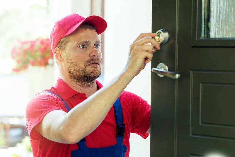 Locksmith technician performing house door lock maintenance